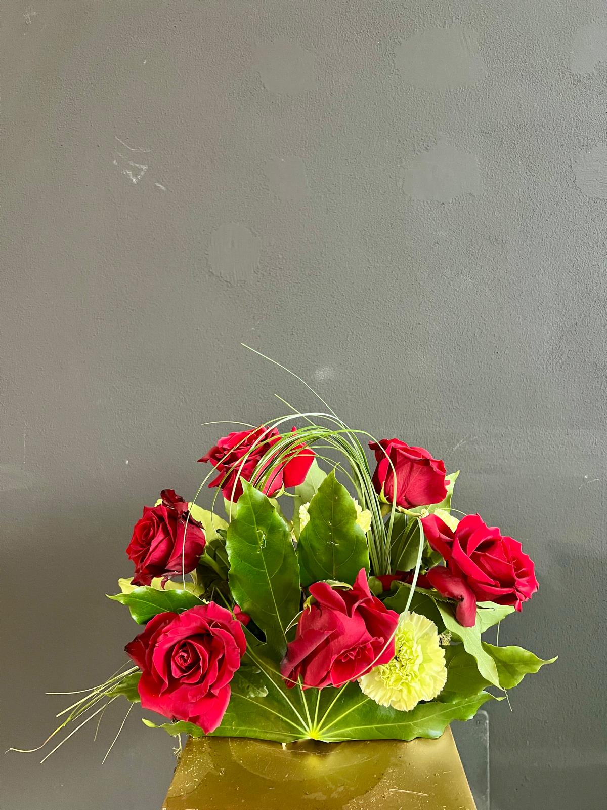 Composizione con rose rosse, garofani, bear grass e foglie di aralia