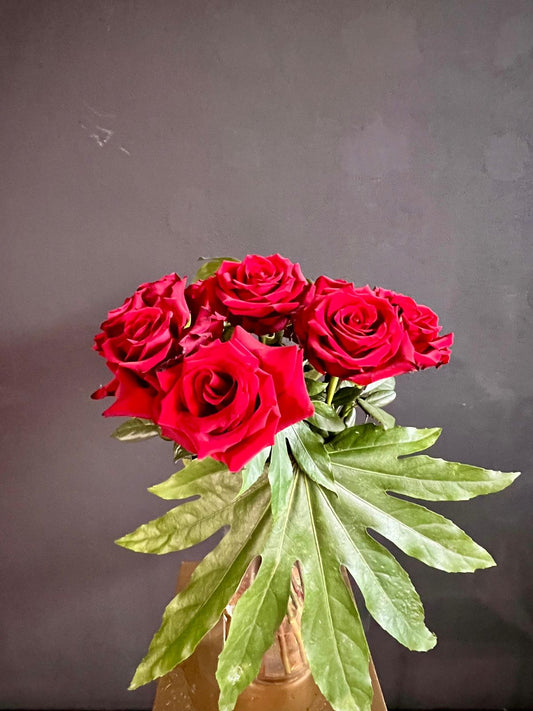 Bouquet di rose rosse e foglie di aralia